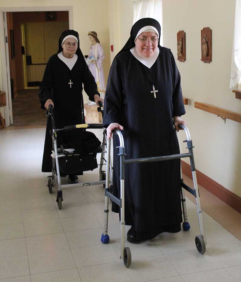 Sister Francesco (l.) and Sister Immaculata look forward to their daily exercise “walks” in the long corridors of our Perpetual Help Health Care Center.